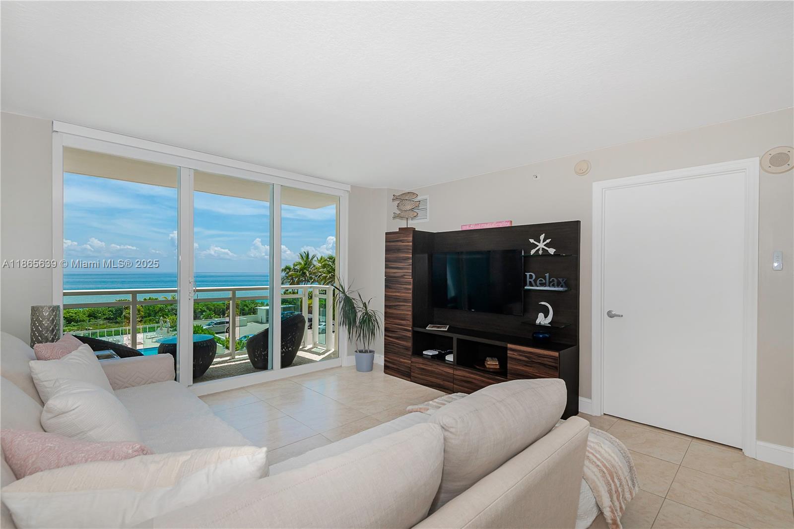6917 Collins Avenue, Unit 511 Miami Beach, FL 33141 - Photo 4 of 24 a living room with furniture and a flat screen tv