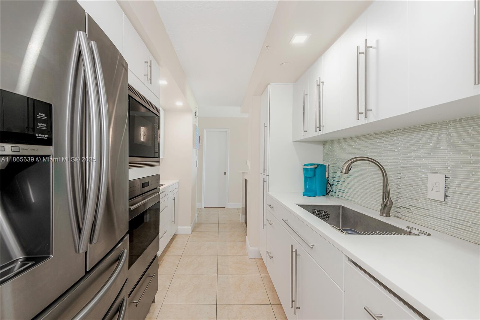6917 Collins Avenue, Unit 511 Miami Beach, FL 33141 - Photo 9 of 24 a kitchen with stainless steel appliances a refrigerator sink and cabinets