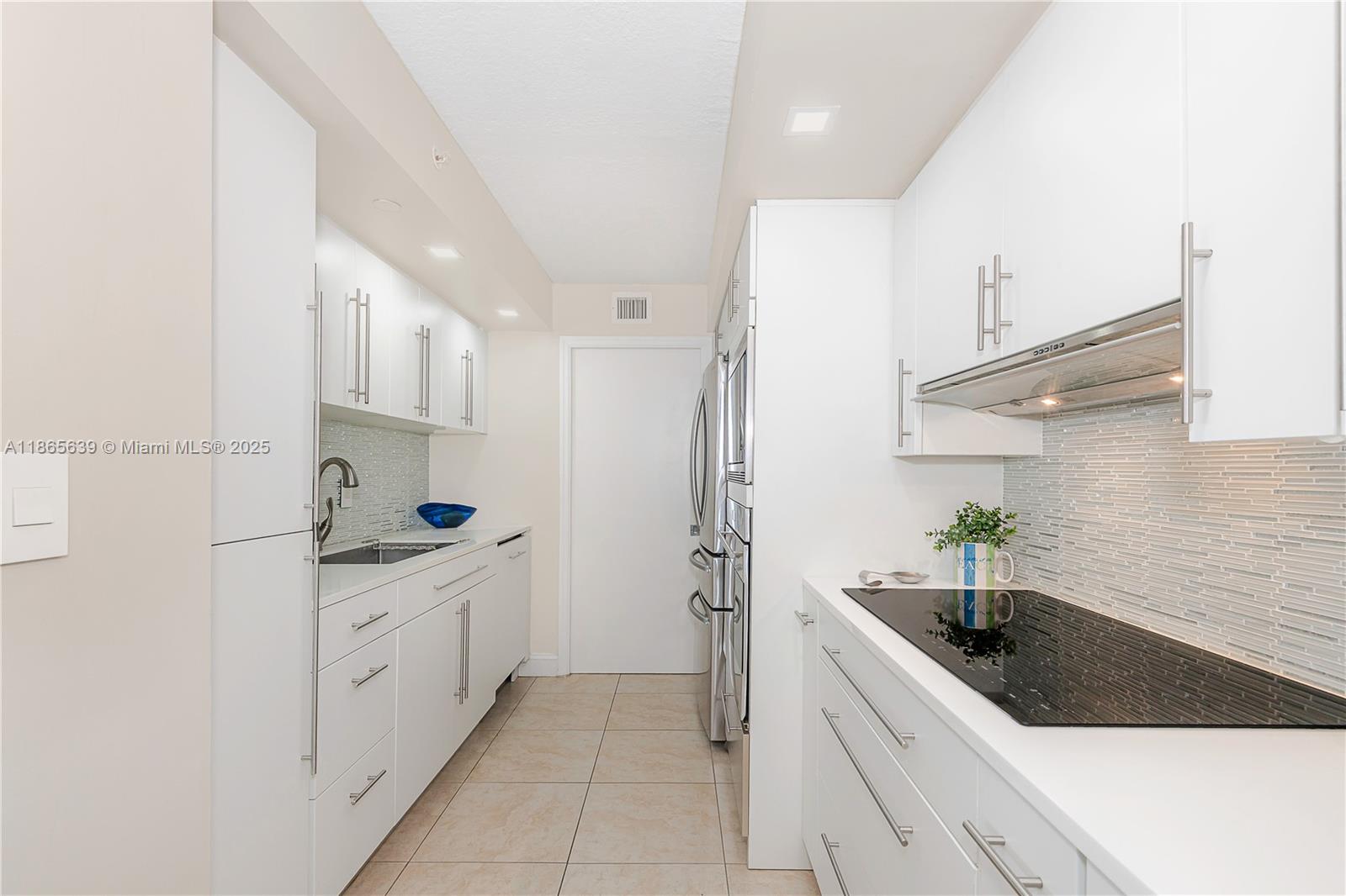 6917 Collins Avenue, Unit 511 Miami Beach, FL 33141 - Photo 10 of 24 a kitchen with granite countertop a sink stove and cabinets