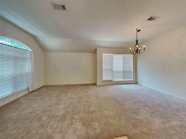 an empty room with a chandelier fan and windows