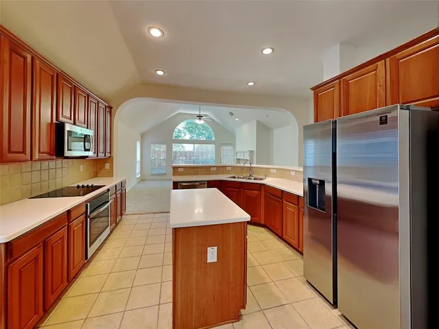 a kitchen with stainless steel appliances granite countertop a refrigerator a sink and wooden cabinets