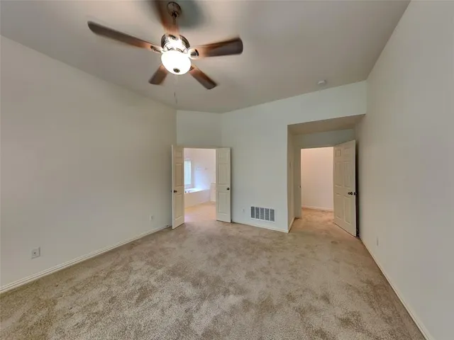 a view of an empty room and chandelier fan
