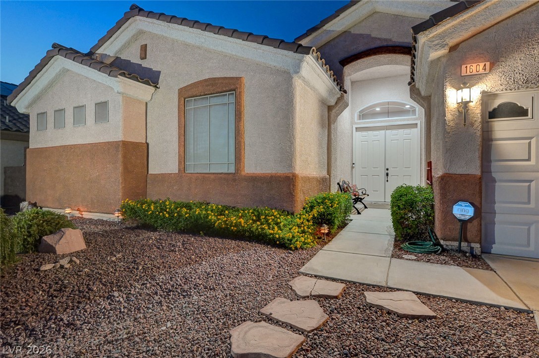 1604 Cattle Ranch Place Henderson, NV 89002 - Photo 83 of 99 A welcoming stucco facade with an arched entryway and inviting landscaping creates curb appeal.
