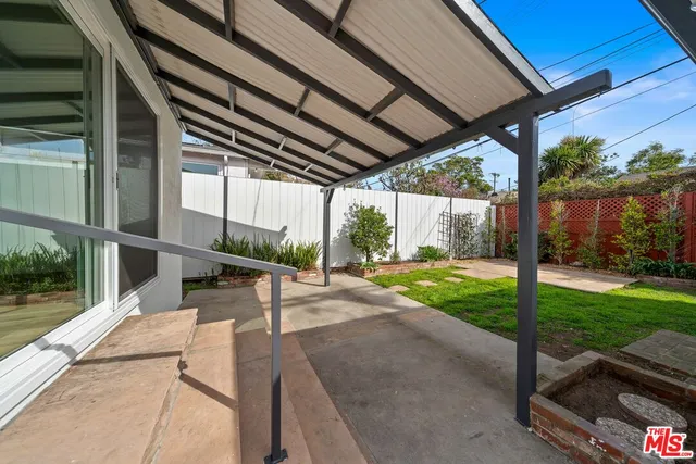 a view of a patio with table and chairs under an umbrella with a big yard