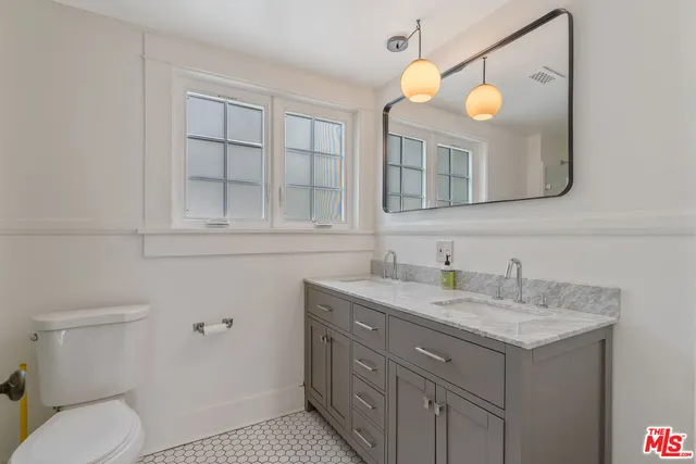 a bathroom with a granite countertop sink a toilet and mirror
