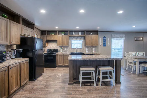 a kitchen with granite countertop kitchen island wooden cabinets and stainless steel appliances