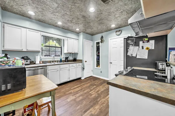 a kitchen with granite countertop a sink cabinets and stainless steel appliances