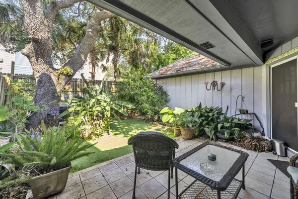 a backyard with table and chairs potted plants and large tree