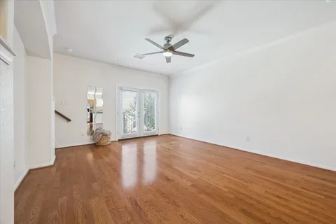 a view of empty room with wooden floor and ceiling fan