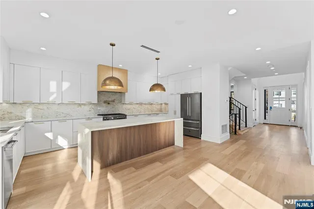 a large kitchen with stainless steel appliances granite countertop a sink a stove and a refrigerator