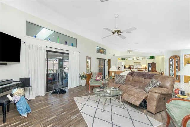 a living room with furniture a flat screen tv and a ceiling fan