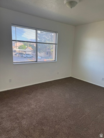 1797 West 950 North, Unit 2 St. George, UT 84770 - Photo 9 of 11 Room featuring a large window with horizontal blinds, neutral wall paint, and a textured brown carpet