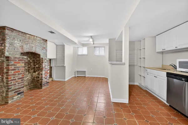 a view of empty room with wooden floor and kitchen
