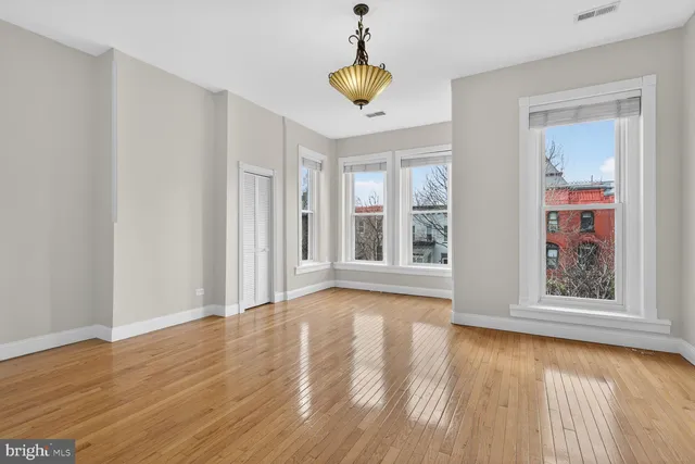 a view of empty room with wooden floor and fan