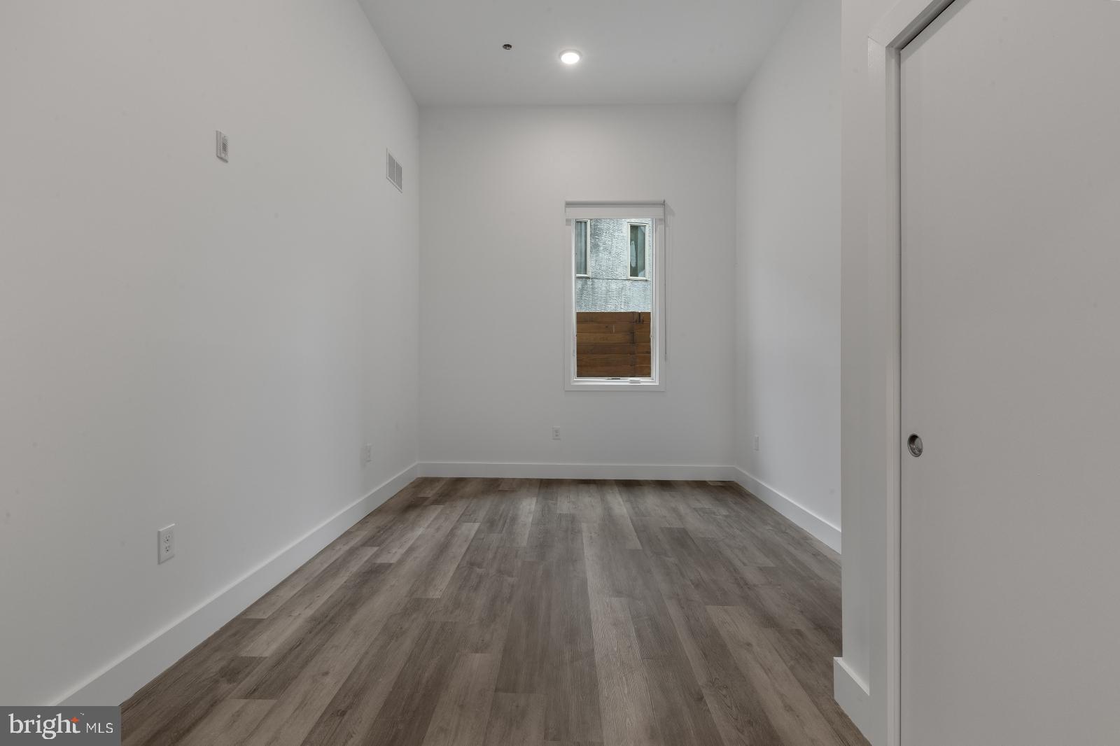 2559 Amber Street, Unit 101 Philadelphia, PA 19125 - Photo 17 of 35 a view of an empty room with wooden floor and a window