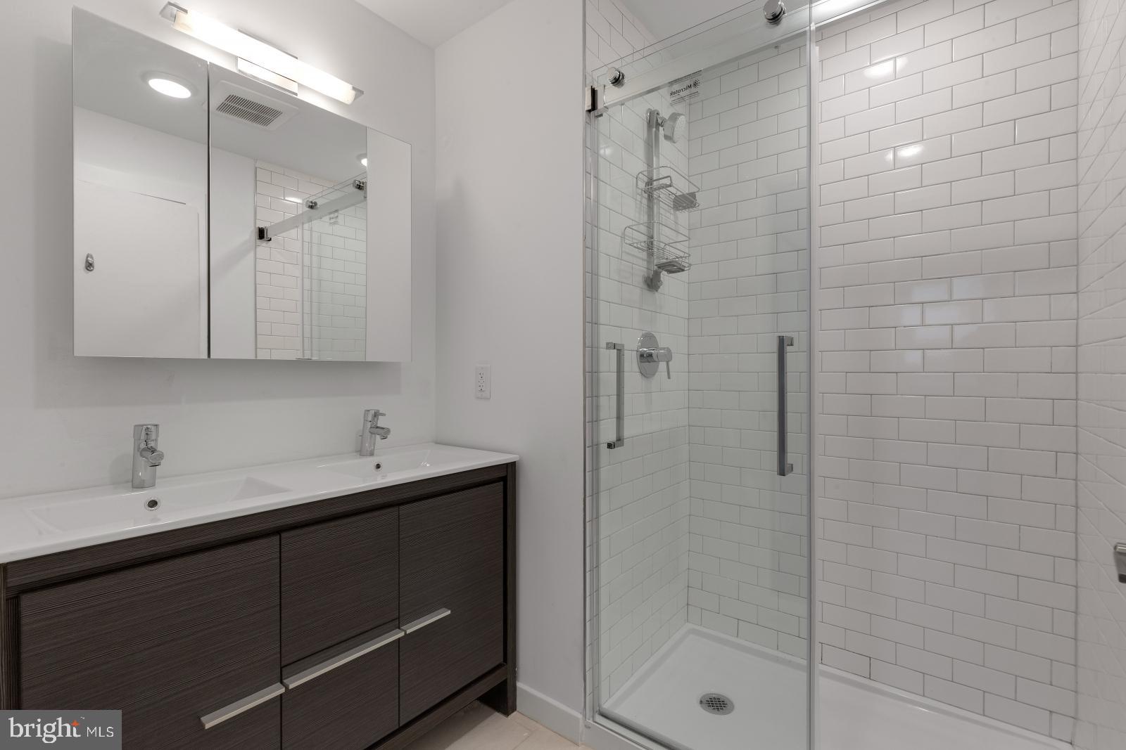 2559 Amber Street, Unit 101 Philadelphia, PA 19125 - Photo 23 of 35 a bathroom with a shower sink and mirror