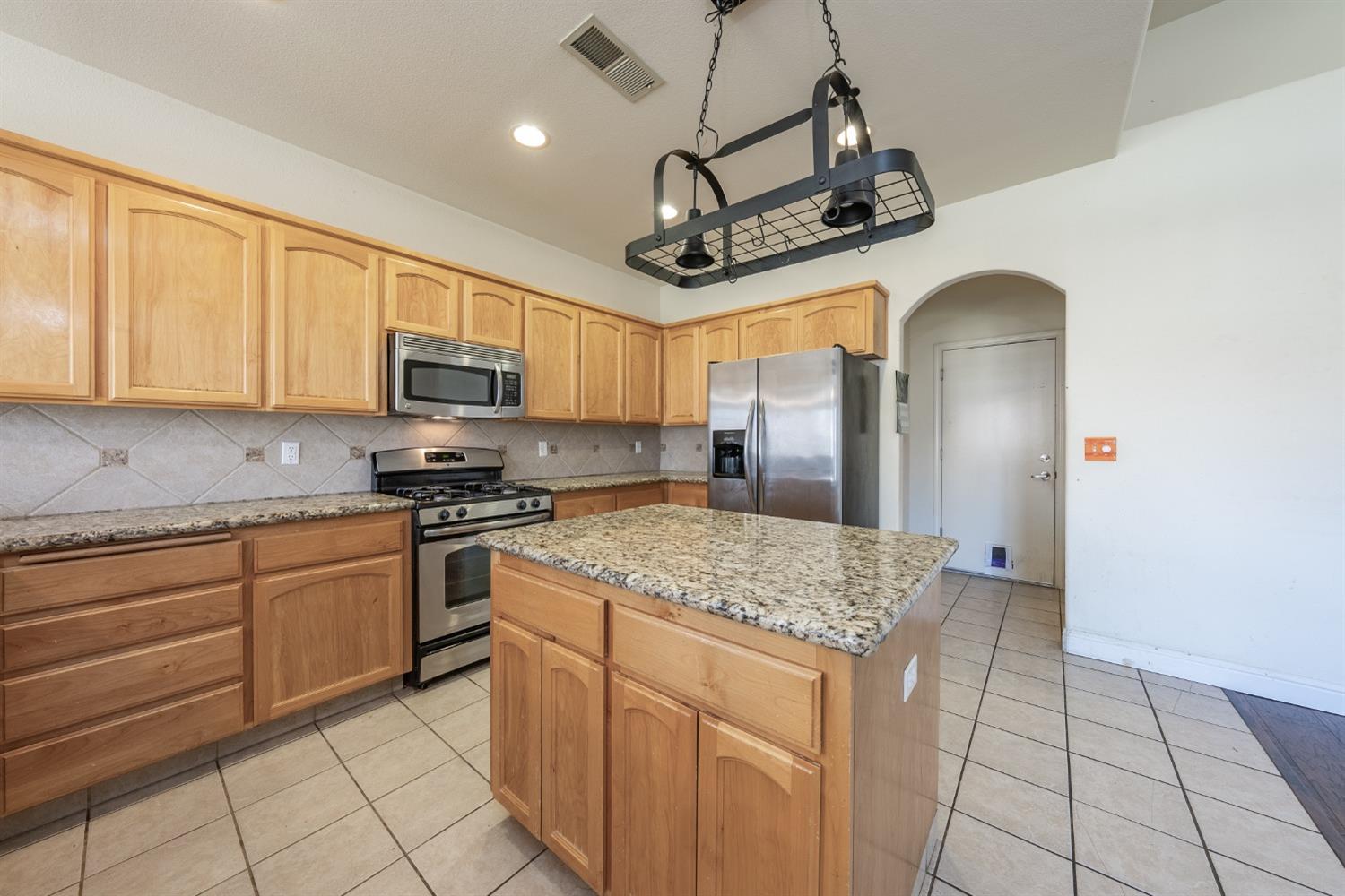 2727 Pear Tree Drive Madera, CA 93637 - Photo 12 of 36 a kitchen with stainless steel appliances granite countertop a sink a stove a refrigerator cabinets and chairs