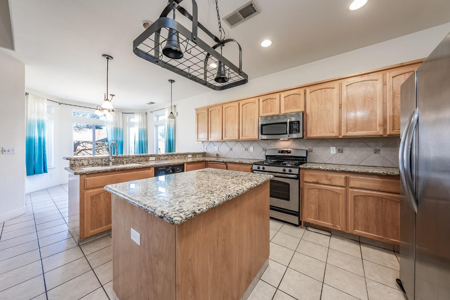 2727 Pear Tree Drive Madera, CA 93637 - Photo 13 of 36 a kitchen with stainless steel appliances granite countertop a sink a stove a microwave and cabinets
