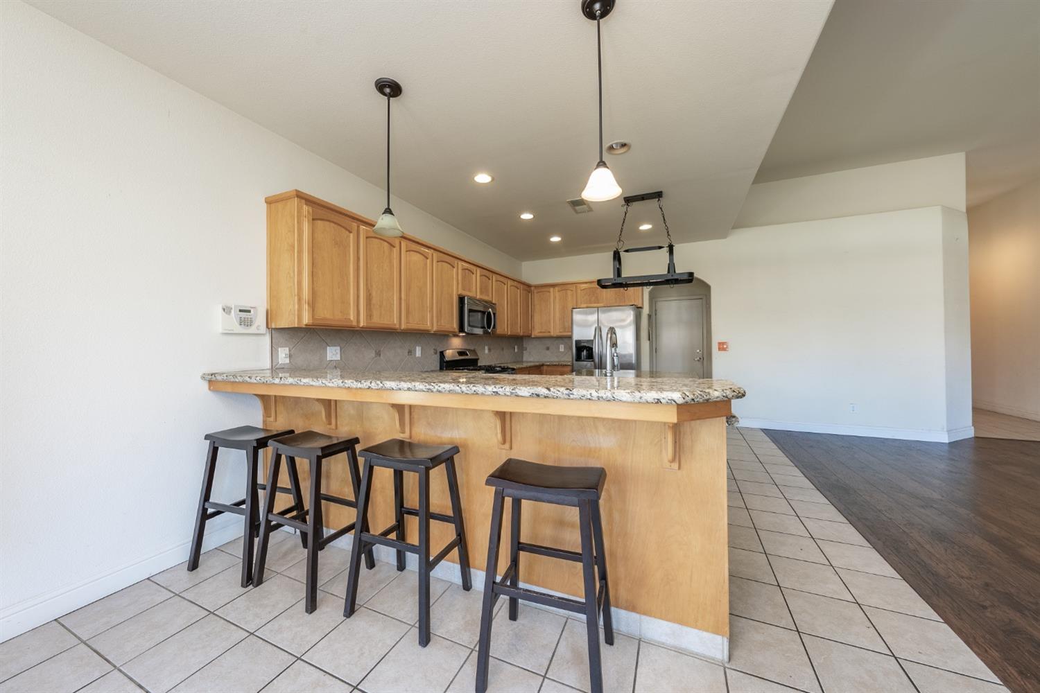 2727 Pear Tree Drive Madera, CA 93637 - Photo 9 of 36 a kitchen with stainless steel appliances granite countertop a sink a stove a refrigerator and island with wooden floor