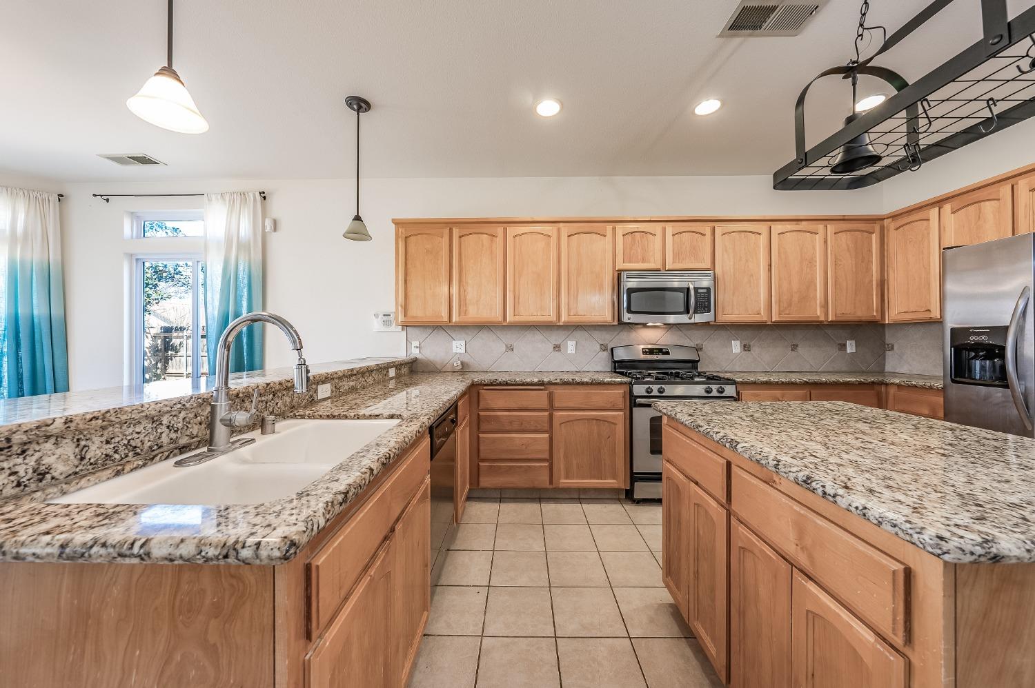 2727 Pear Tree Drive Madera, CA 93637 - Photo 10 of 36 a kitchen with stainless steel appliances granite countertop a sink stove and microwave