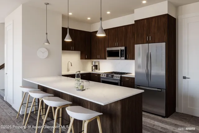 a kitchen with stainless steel appliances a table chairs refrigerator and microwave