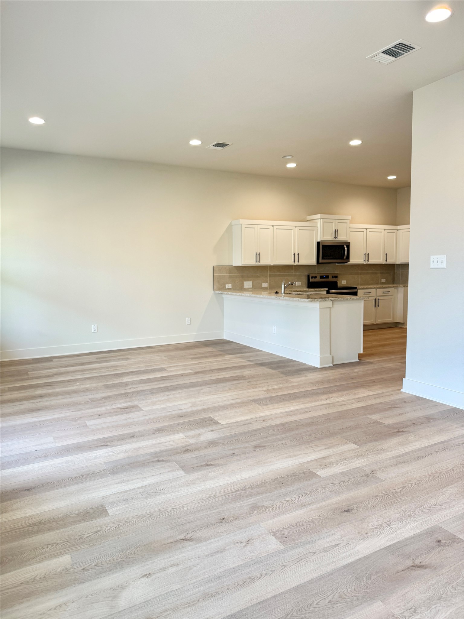 108 Zayd Court, Unit B Jarrell, TX 76537 - Photo 5 of 21 a view of kitchen with kitchen island stainless steel appliances wooden floor and living room view