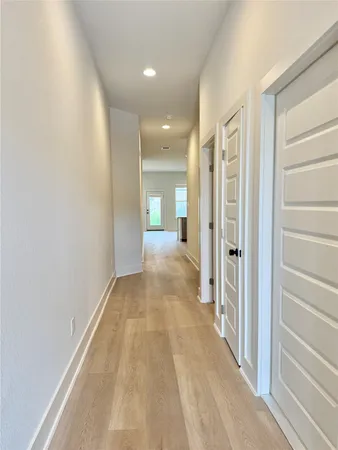 a view of a hallway with wooden floor and a bathroom