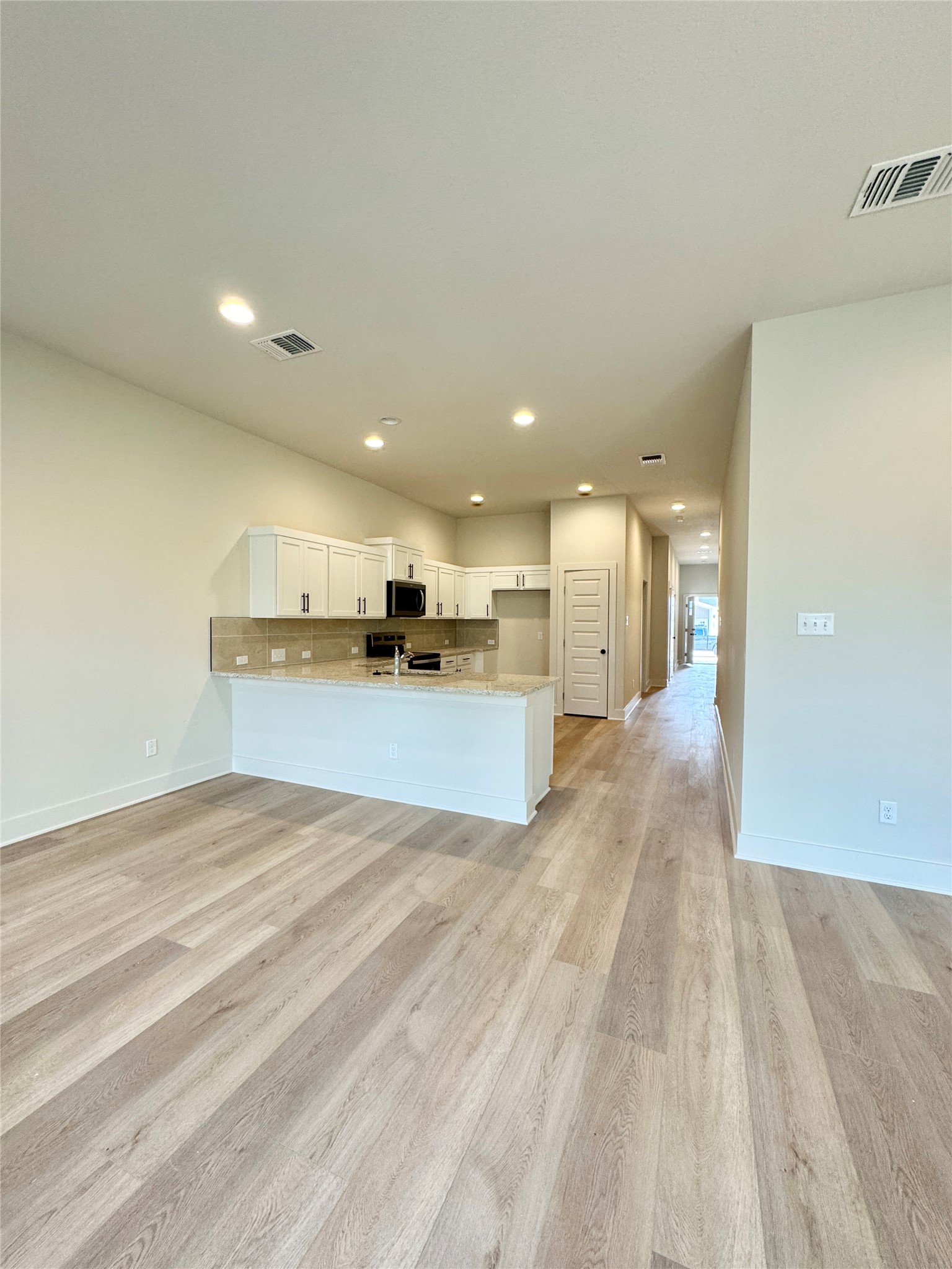 108 Zayd Court, Unit B Jarrell, TX 76537 - Photo 9 of 21 a view of a kitchen with kitchen island a sink wooden floor and a refrigerator