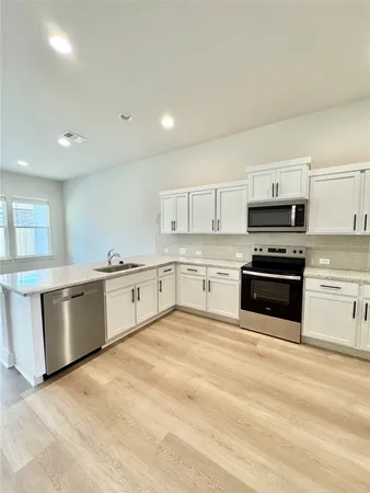 a large kitchen with granite countertop a stove top oven and cabinets