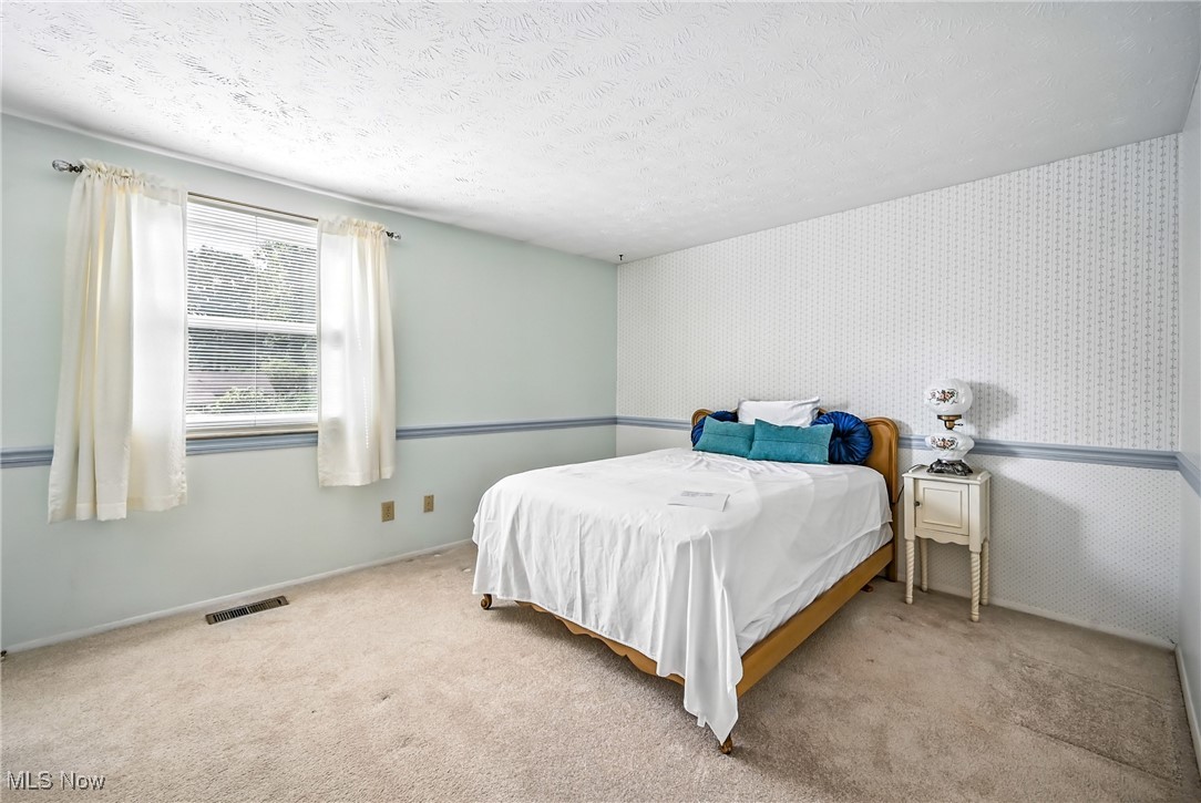 7797 Raglan Drive Northeast Warren, OH 44484 - Photo 39 of 50 Bedroom featuring carpet floors, a textured ceiling, and wallpapered walls