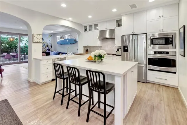 a kitchen with stainless steel appliances a dining table chairs microwave and refrigerator