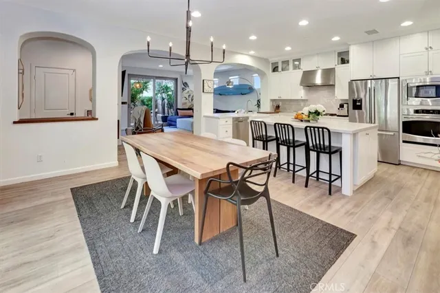 a kitchen with stainless steel appliances kitchen island granite countertop a table chairs and a refrigerator