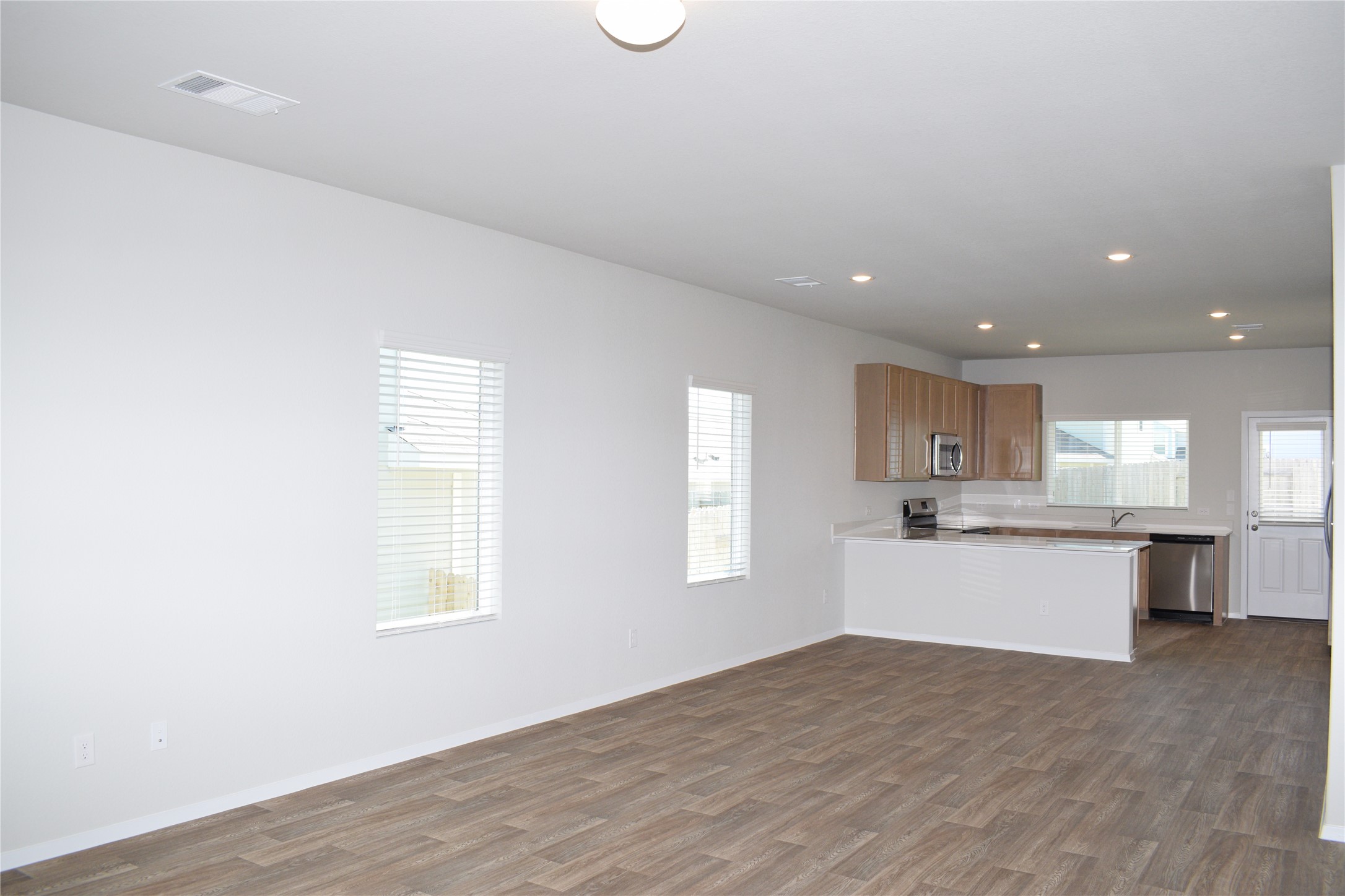 2705 Towy Road Manor, TX 78653 - Photo 29 of 30 Kitchen with light countertops, open floor plan, a peninsula, dark wood finished floors, and stainless steel appliances