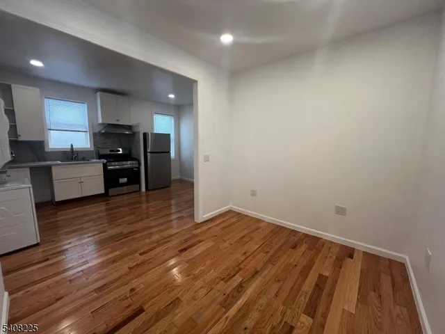 a view of kitchen with cabinets wooden floor and stainless steel appliances