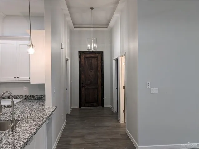 a view of hallway with granite countertop cabinets and wooden floor
