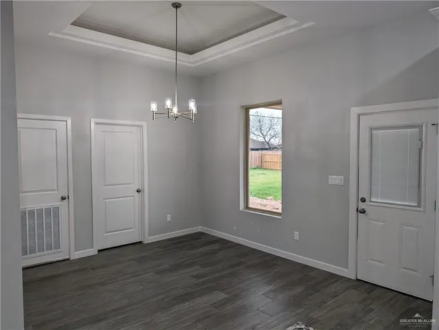 an empty room with wooden floor a chandelier fan and windows