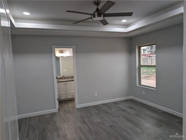 an empty room with wooden floor closet and windows