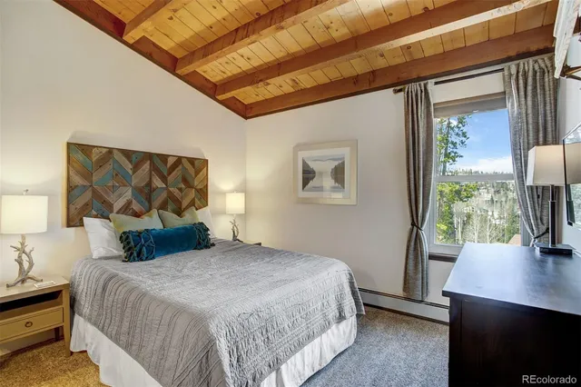 a bedroom with a bed and a dresser next to a window