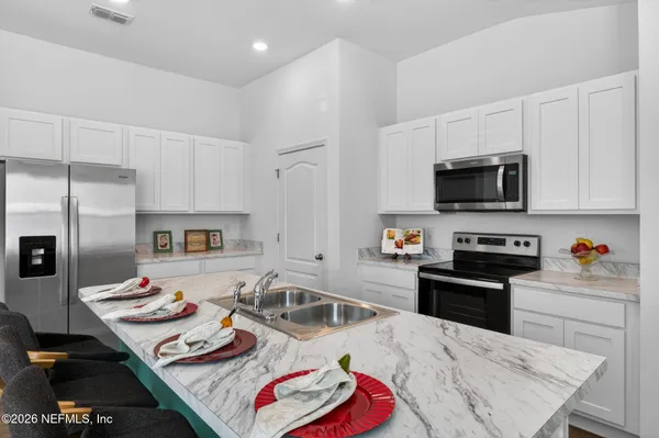 a living room with white cabinets furniture and a kitchen view