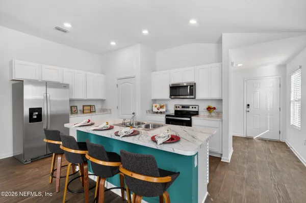 a kitchen that has a table chairs appliances and wooden floor