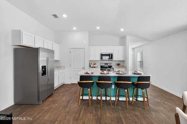 a kitchen with stainless steel appliances a dining table chairs microwave and refrigerator