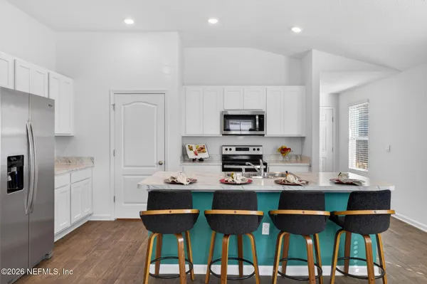 a kitchen with a dining table chairs refrigerator and microwave