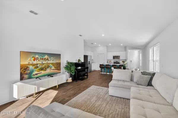 a living room with furniture kitchen view and a window