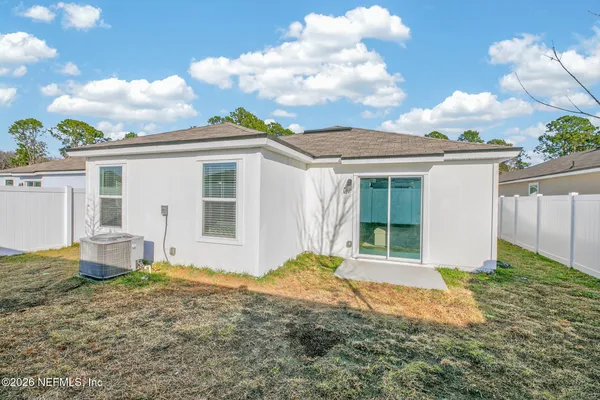 a view of a white house next to a yard with big trees