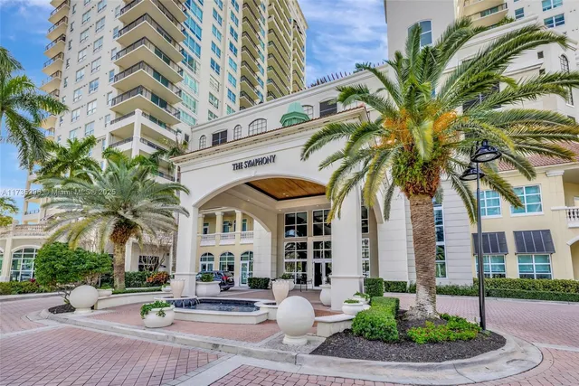 a front view of a building with garden and trees