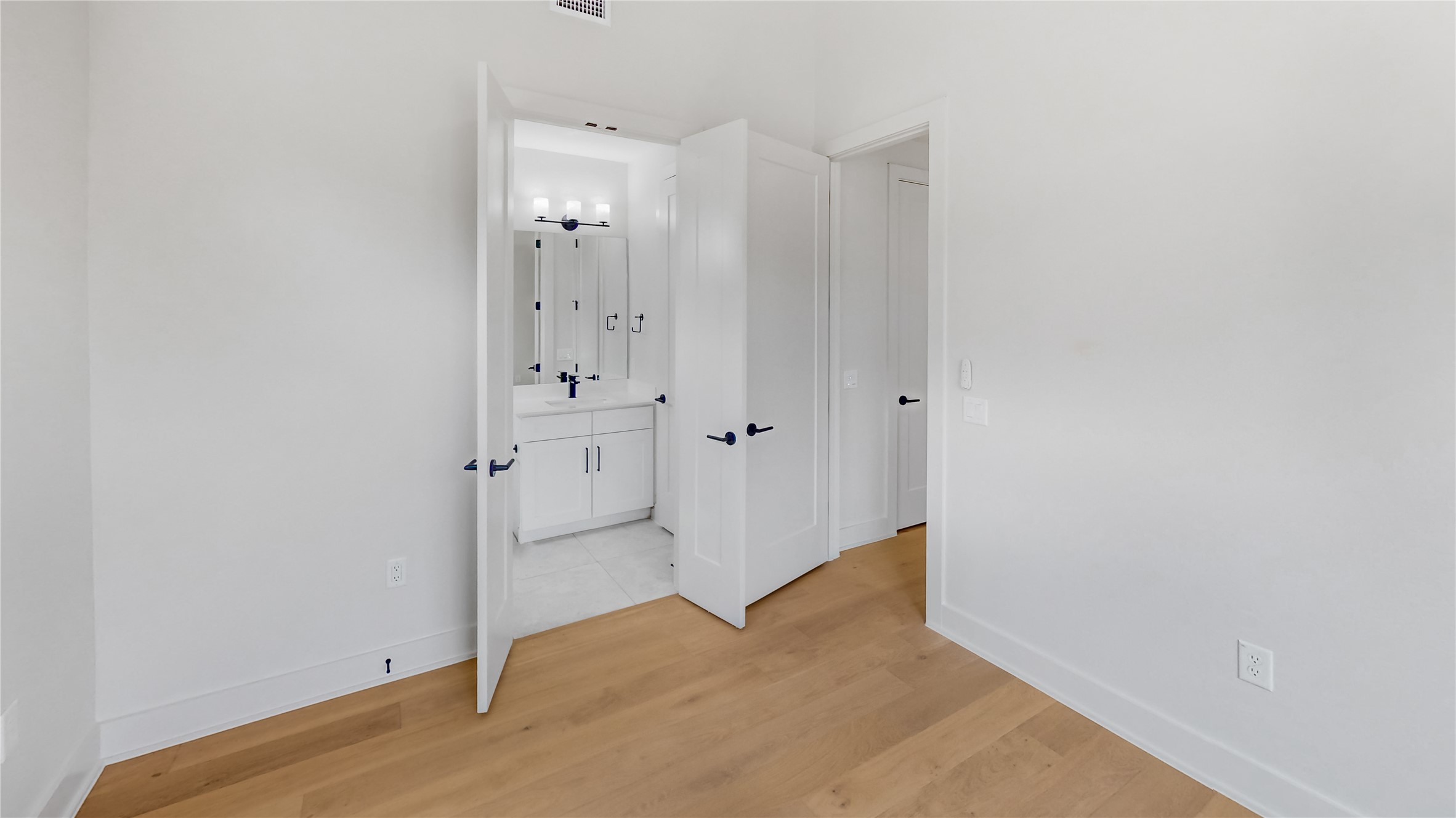 4424 Hank Avenue, Unit 2 Austin, TX 78745 - Photo 7 of 11 Hardwood flooring extends into a well-appointed bathroom with a vanity and modern fixtures.