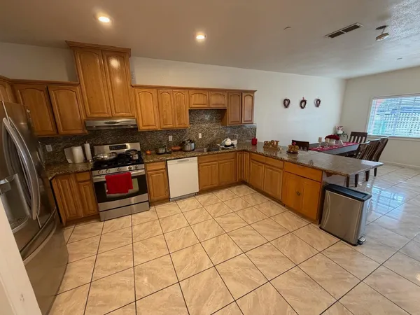 a kitchen with stainless steel appliances granite countertop a stove a sink dishwasher and a refrigerator