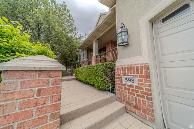 598 Hollow Creek Road Draper, UT 84020 - Photo 14 of 110 Brick and stucco exterior featuring a built-in outdoor lantern and a garage with a panel door