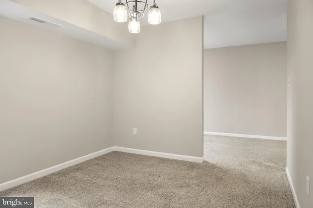 a view of an empty room with a chandelier fan