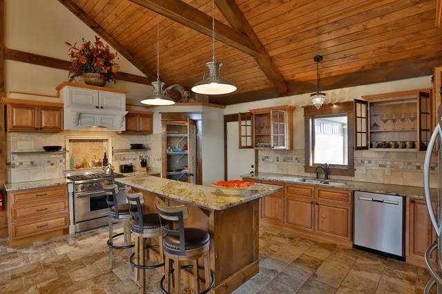 a kitchen with stainless steel appliances granite countertop a stove a sink dishwasher and a refrigerator with wooden cabinets